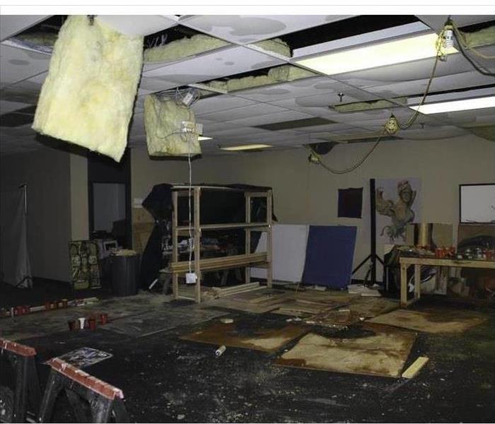 Roof collapsed in a building, many pieces of ceiling tiles on floor, floor wet