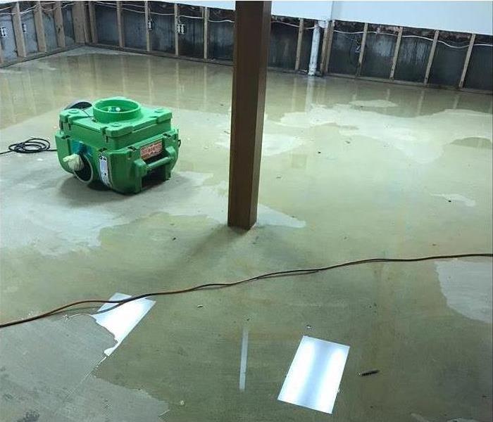 Flood cuts done inside a commercial property, water on concrete floor, dehumidifier in middle of the room